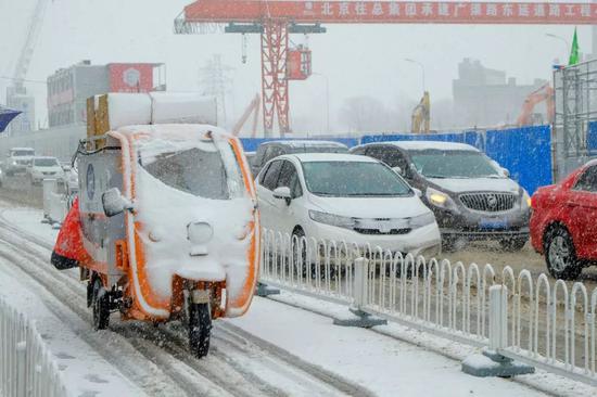  2020年2月14日，北京迎來降雪天氣，快遞小哥忙著送貨。圖 | 視覺中國